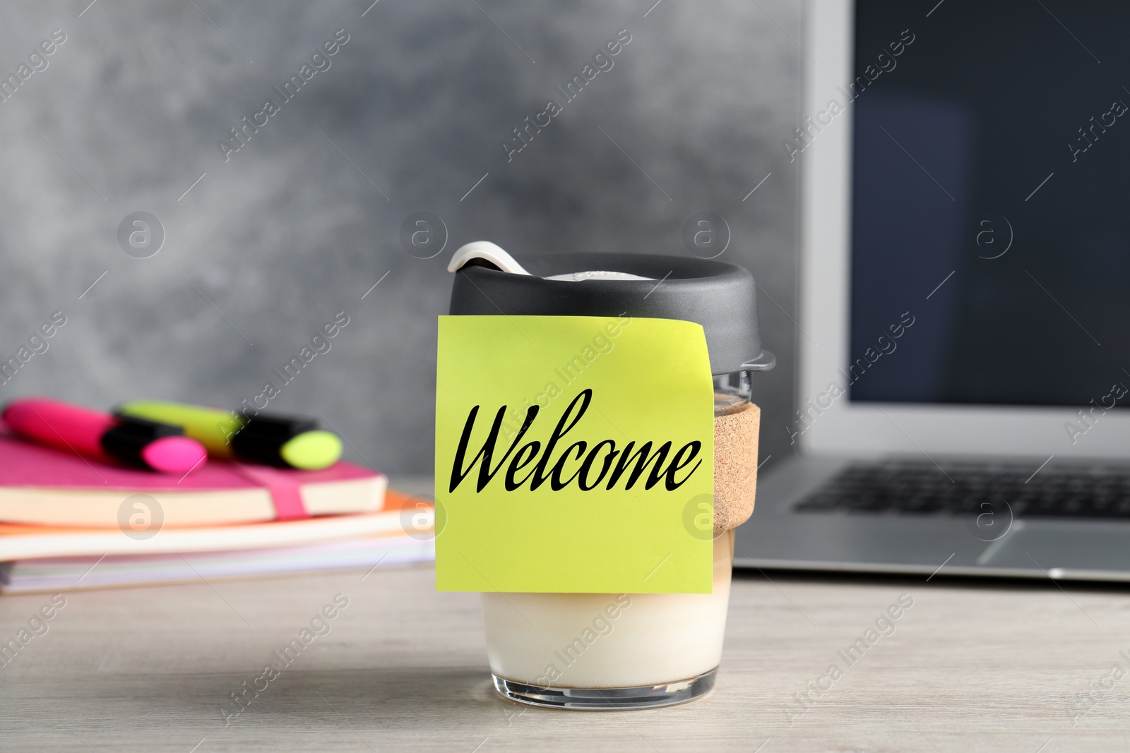 Image of Sticky note with word Welcome attached to cup of coffee on office desk