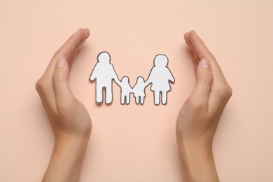 Woman with paper family cutout on beige background, top view