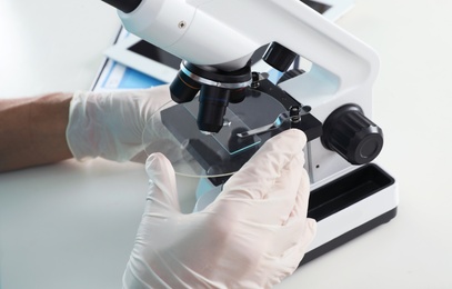 Photo of Male doctor using microscope at table, closeup. Medical object