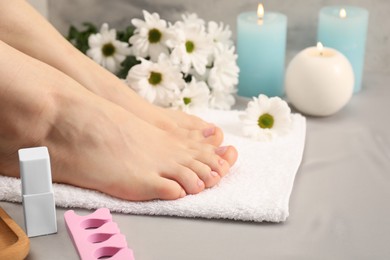 Photo of Woman with neat toenails after pedicure procedure on grey silky fabric, closeup