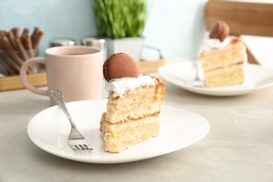 Photo of Piece of delicious homemade cake with caramel sauce and macaron on table