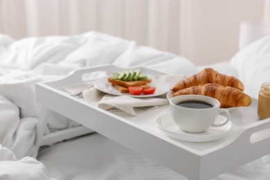 Photo of Good morning. Tray with tasty breakfast on bed at home