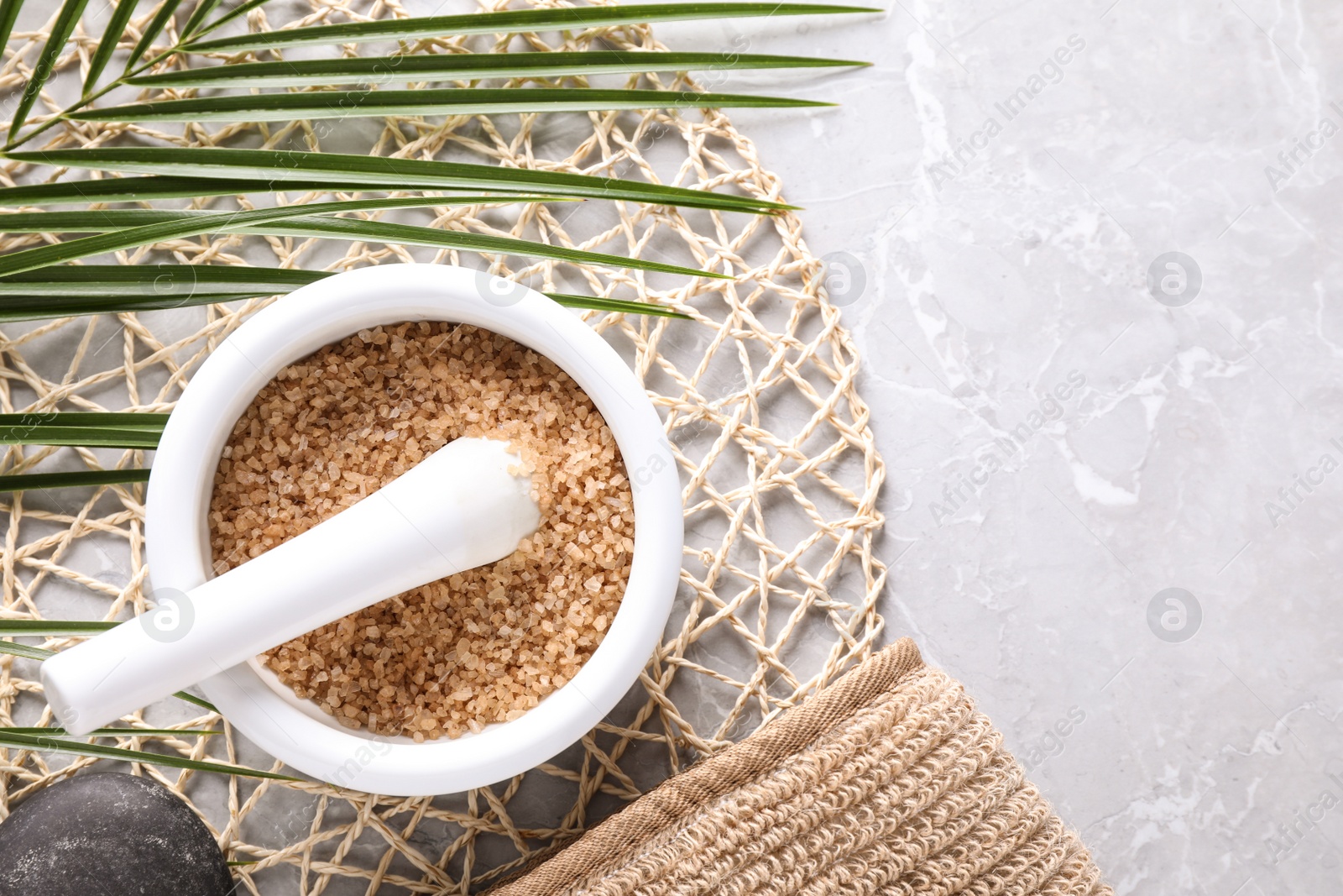 Photo of Flat lay composition with brown sea salt on marble background, space for text. Spa treatment