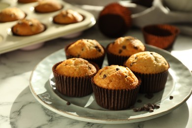 Photo of Delicious sweet muffins with chocolate chips on white marble table