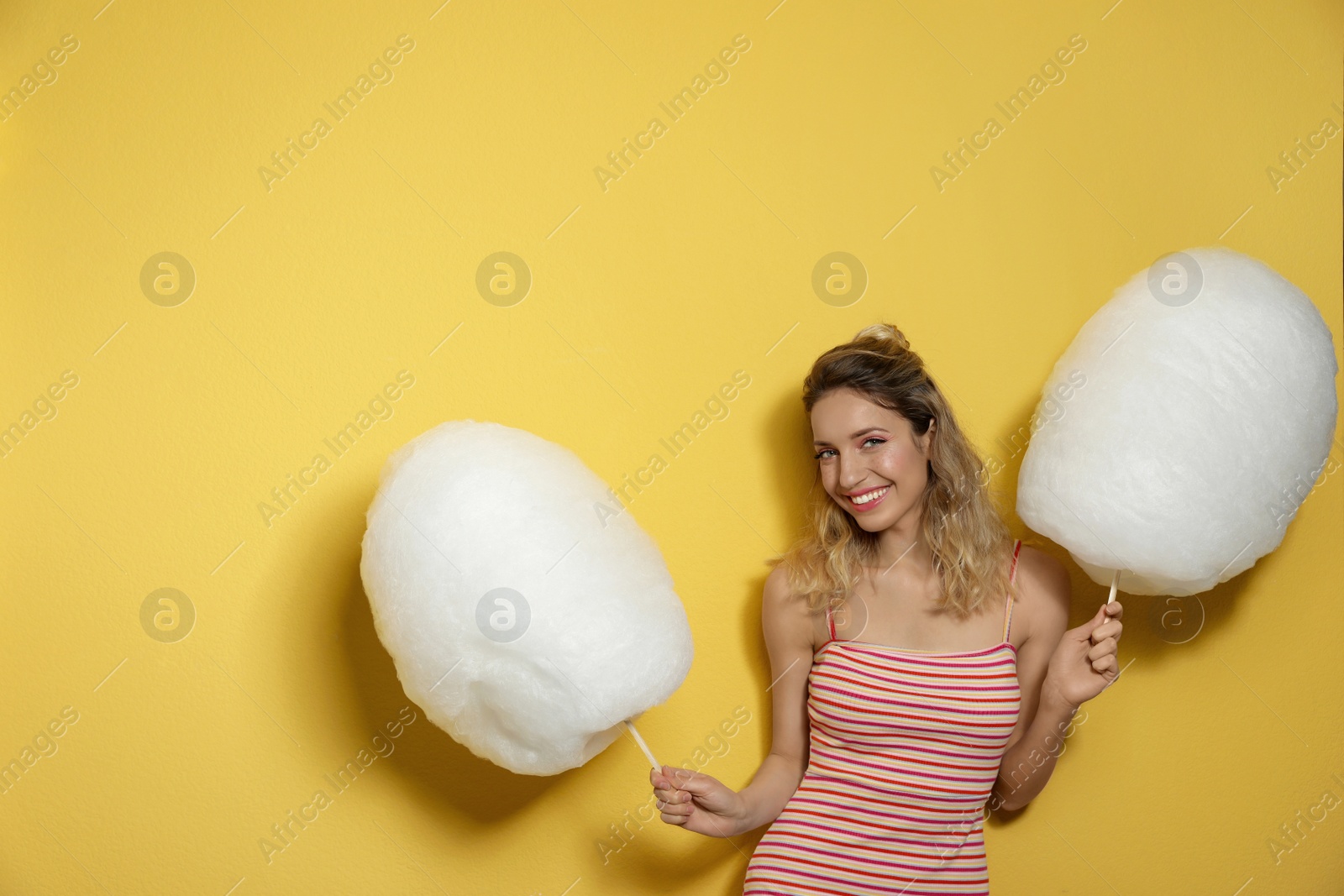 Photo of Portrait of pretty young woman with cotton candy on yellow background