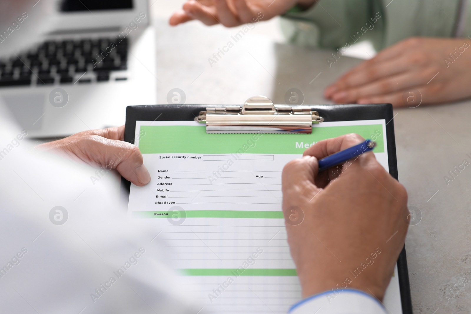 Photo of Doctor filling patient's medical card in clinic, closeup