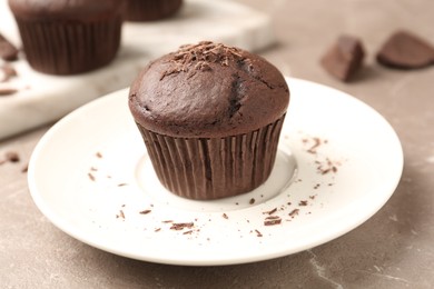 Delicious cupcake with chocolate crumbles on beige marble table, closeup