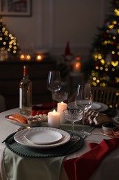 Photo of Christmas table setting with burning candles, appetizers and dishware indoors