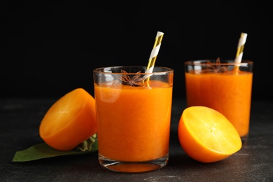 Tasty persimmon smoothie with anise and fresh fruits on black table, closeup