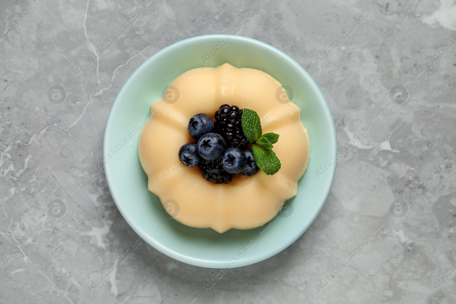 Photo of Delicious semolina pudding with berries on light grey table, top view