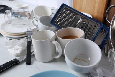 Many dirty utensils and dishware on countertop in messy kitchen