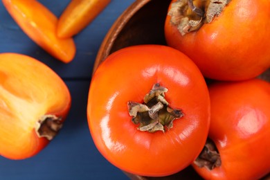 Photo of Delicious ripe persimmons on blue table, top view