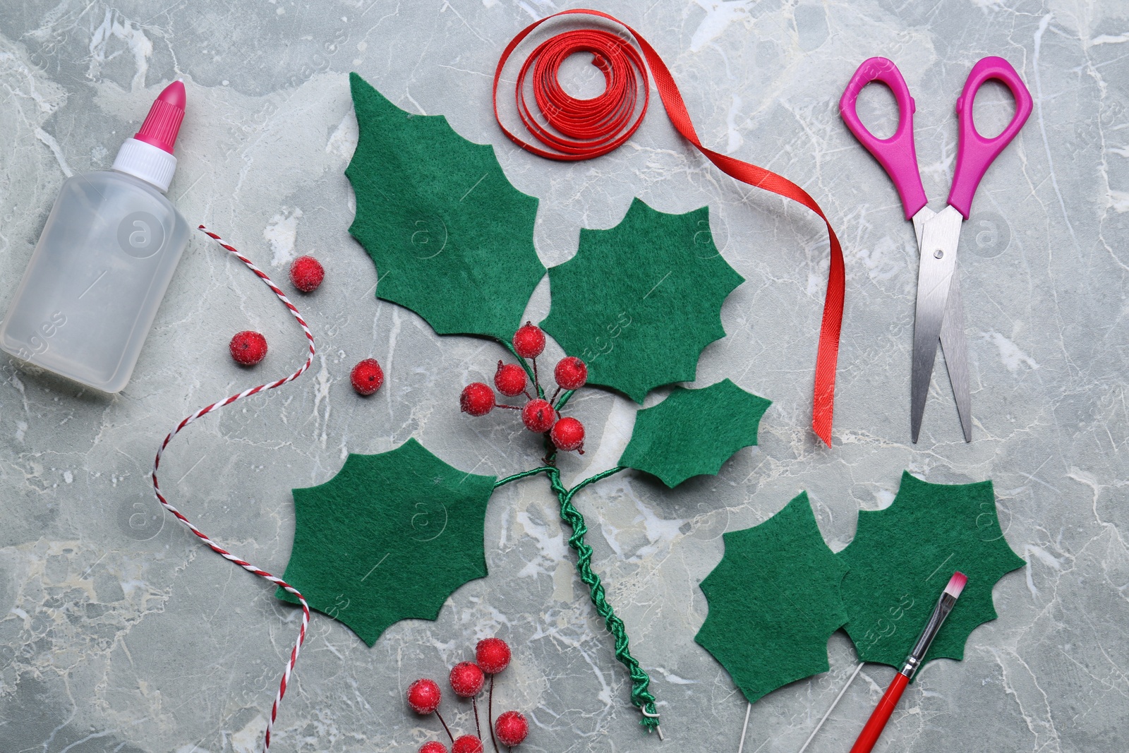 Photo of Set of instruments and materials for making mistletoe branch on grey table, flat lay