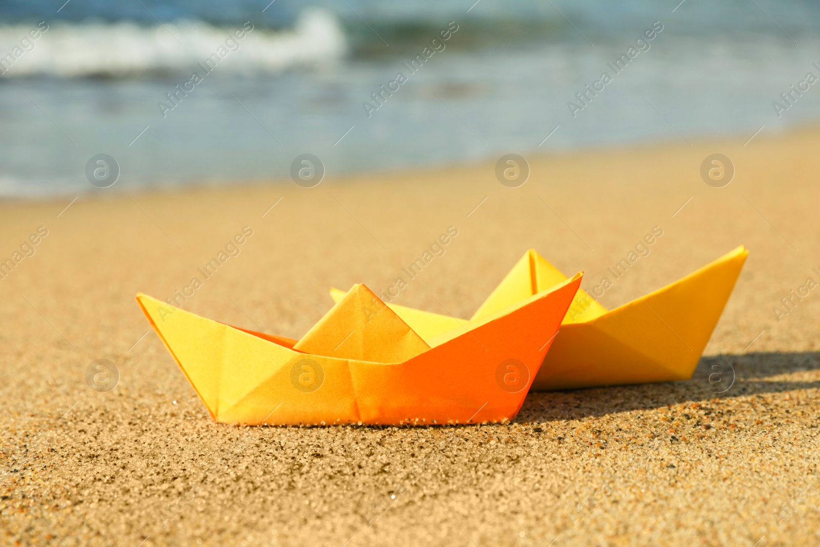 Photo of Bright color paper boats on sandy beach near sea