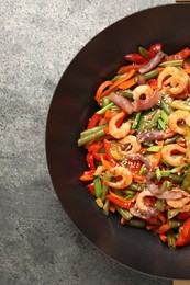 Shrimp stir fry with vegetables in wok on grey table, top view