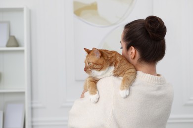 Photo of Woman with cute cat at home, back view. Space for text