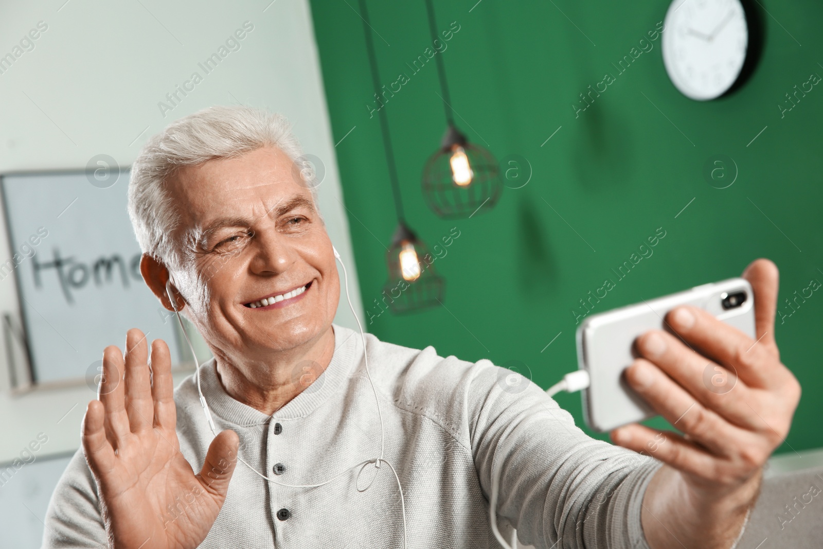 Photo of Mature man using video chat on mobile phone at home