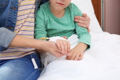 Woman visiting her little child with intravenous drip in hospital, closeup