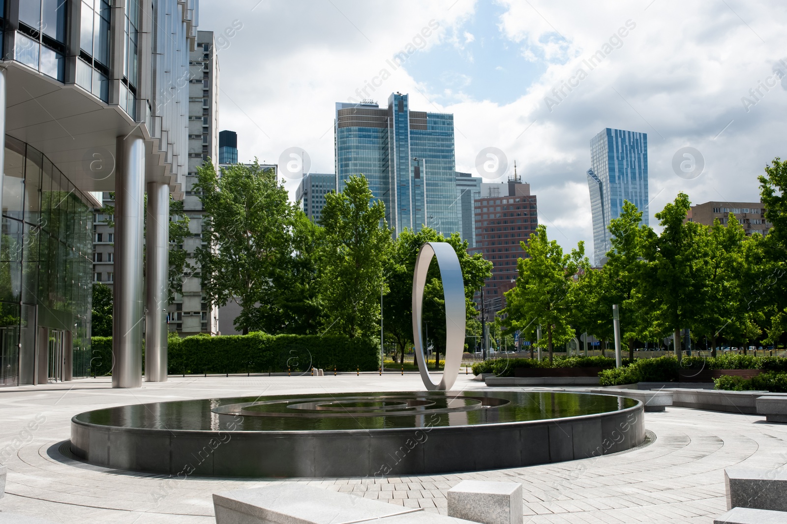 Photo of Beautiful fountain near buildings in city under cloudy sky