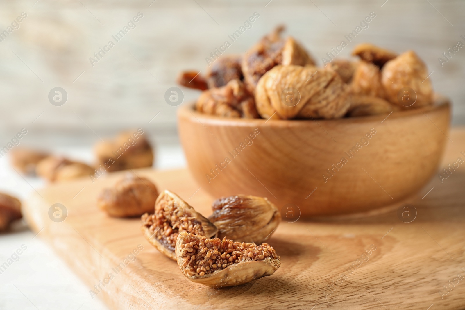 Photo of Wooden board with tasty dried figs on light table. Space for text
