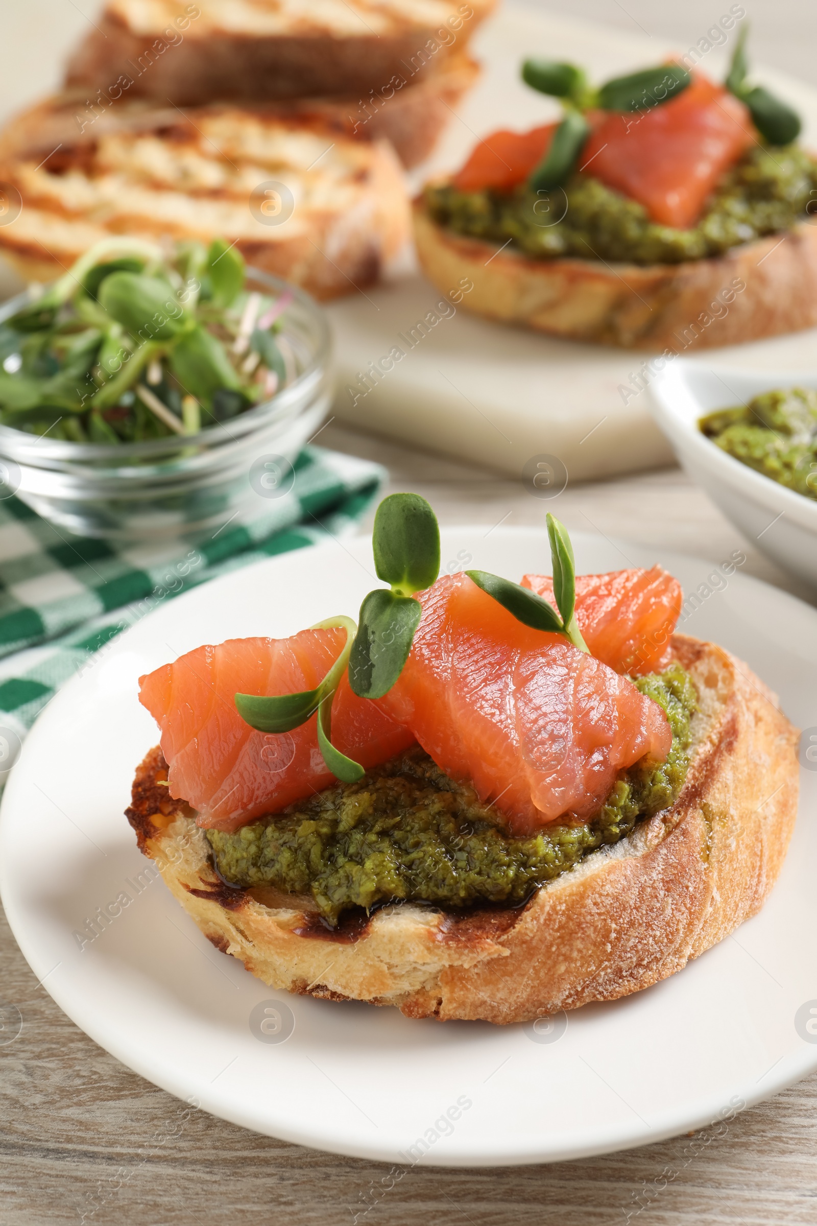 Photo of Delicious bruschetta with salmon and pesto sauce on wooden table