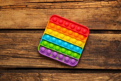 Photo of Rainbow pop it fidget toy on wooden table, top view