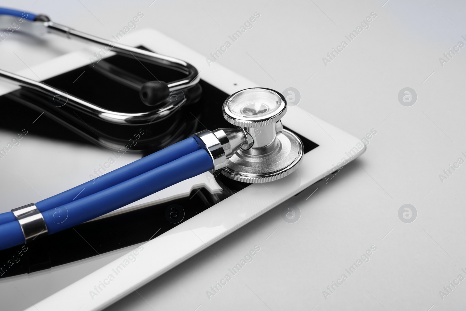 Photo of Medical stethoscope and tablet on white background, closeup