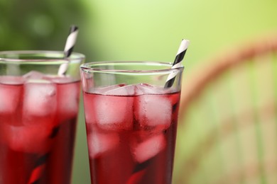 Photo of Refreshing hibiscus tea with ice cubes in glasses on blurred green background, closeup. Space for text