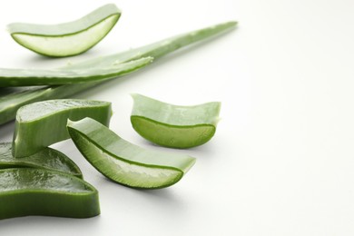 Fresh aloe vera pieces on white table, space for text