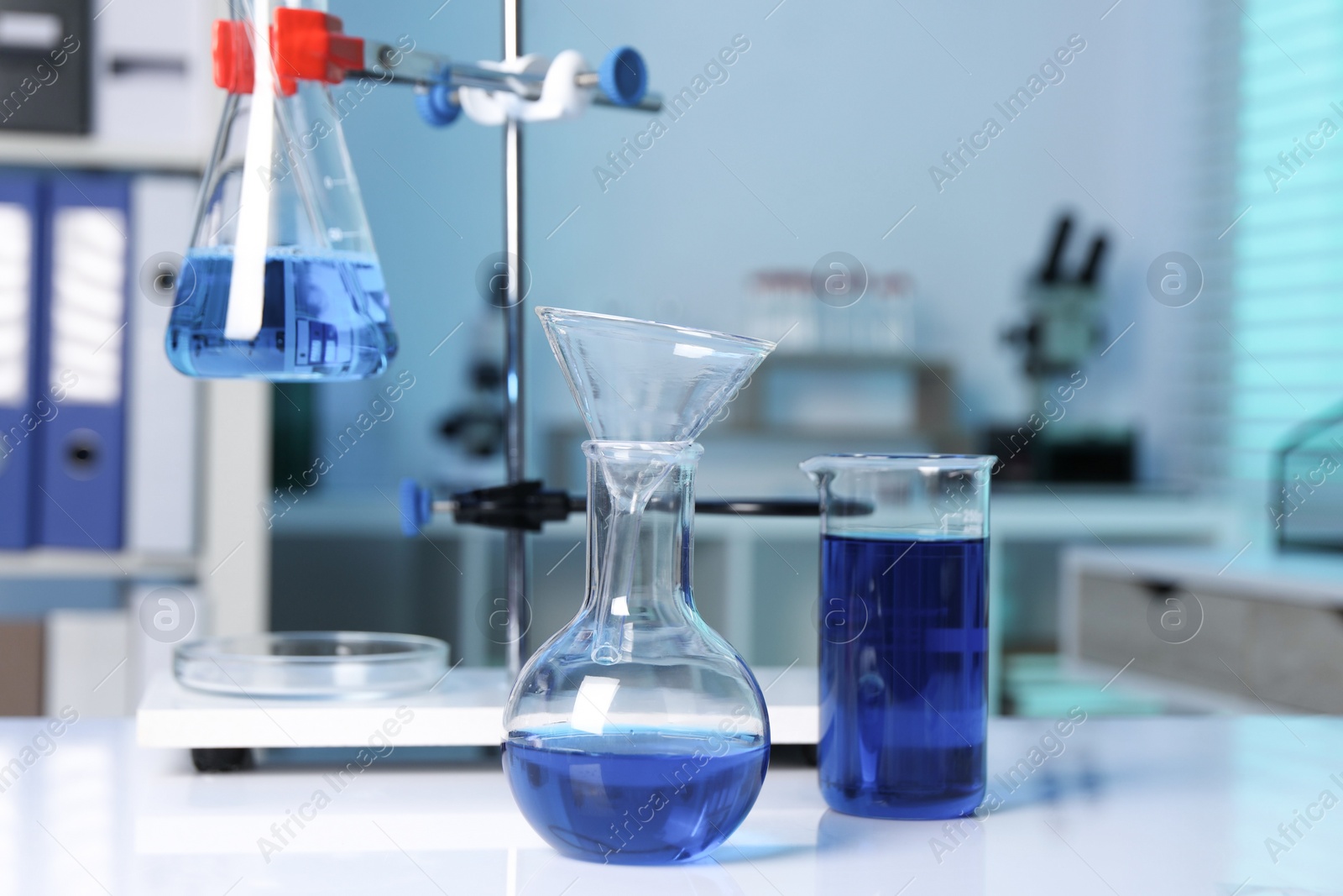 Photo of Laboratory analysis. Flasks and beaker with blue liquid on white table indoors