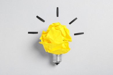 Crumpled paper as lamp bulb on white background, top view. Creative concept