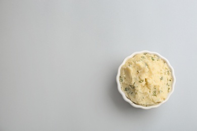 Bowl of tasty mashed potato on light background, top view with space for text