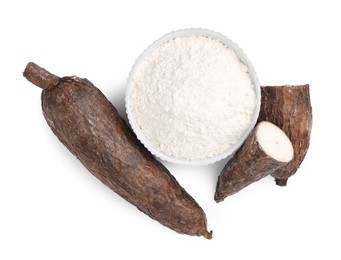 Photo of Bowl with cassava flour and roots isolated on white, top view