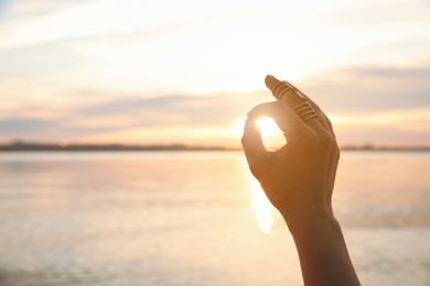 Young woman enjoying beautiful sunset near river, closeup view with space for text. Nature healing power