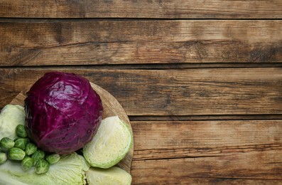 Photo of Different types of cabbage on wooden table, top view. Space for text