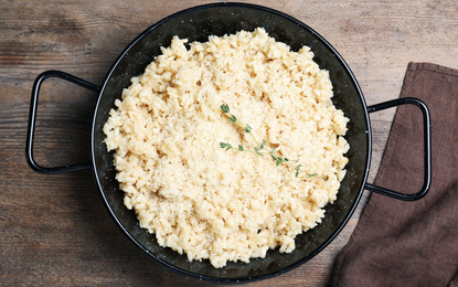 Delicious risotto with cheese on wooden table, top view