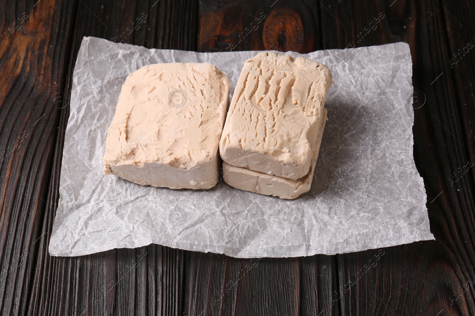 Photo of Pieces of fresh compressed yeast on wooden table