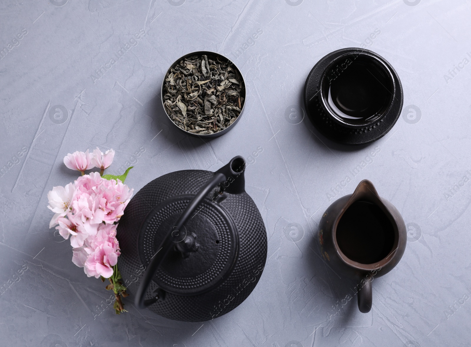 Photo of Beautiful set for traditional tea ceremony and sakura flowers on light grey table, flat lay