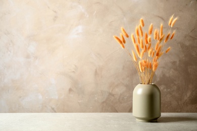 Dried flowers in vase on table against beige background. Space for text