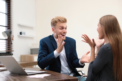 Happy young people playing online lottery using laptop in office