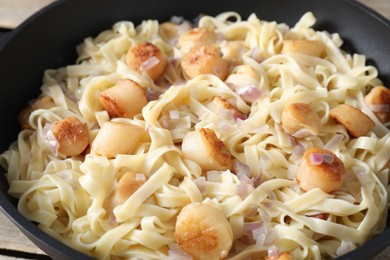 Photo of Delicious scallop pasta with onion in bowl, closeup