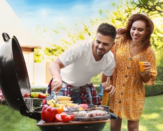 Young man and woman with drinks near barbecue grill outdoors