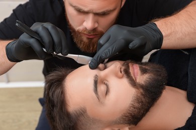 Professional hairdresser working with client in barbershop, closeup