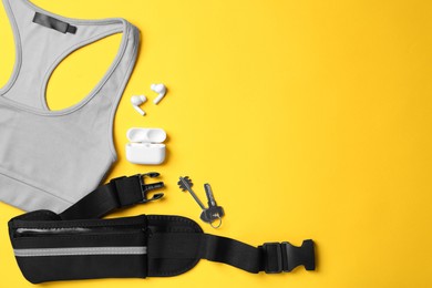 Flat lay composition with stylish black waist bag on yellow background, space for text
