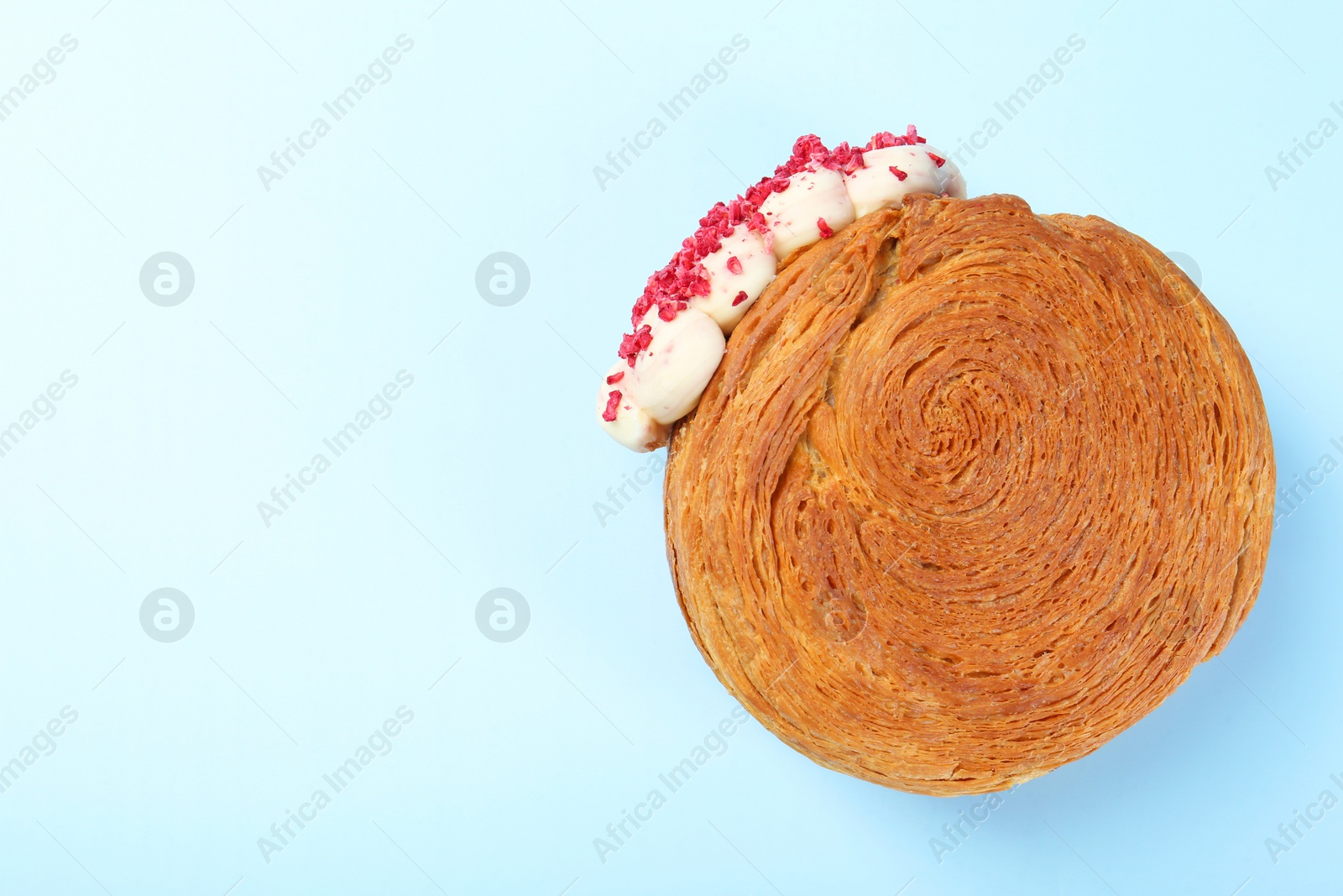 Photo of One supreme croissant with cream on light blue background, top view with space for text. Tasty puff pastry