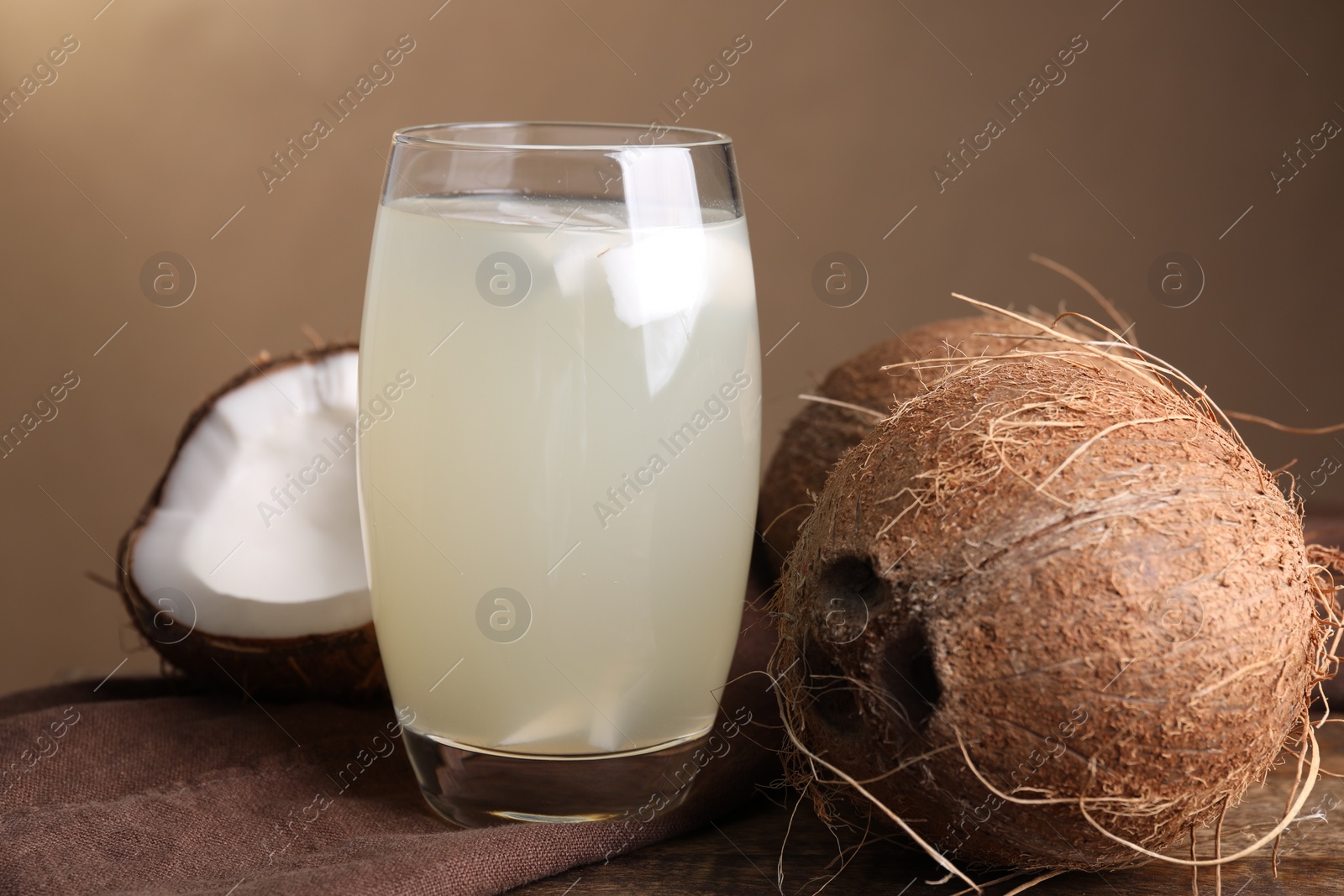 Photo of Glass of coconut water and nuts on wooden table