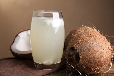 Glass of coconut water and nuts on wooden table