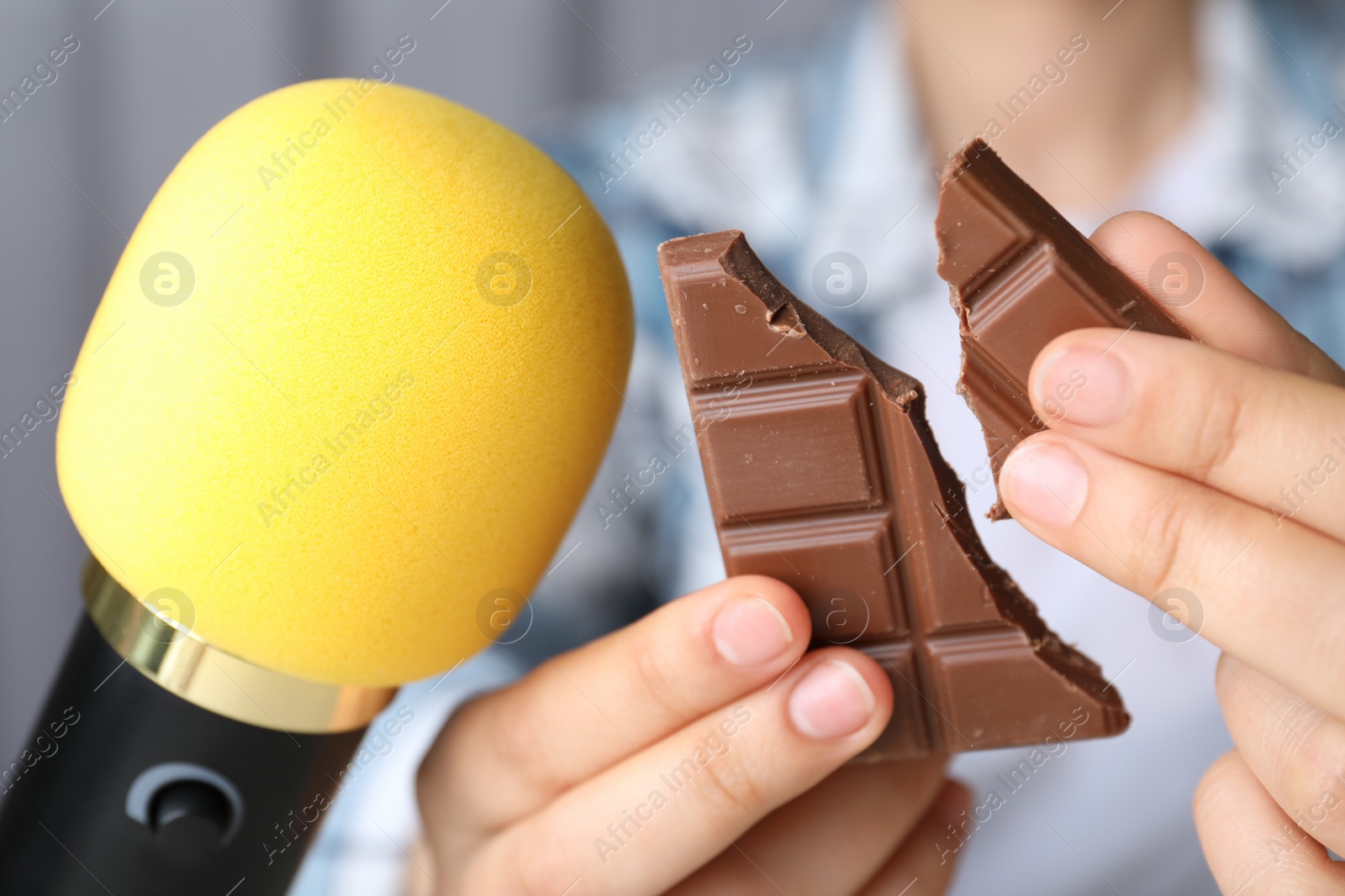 Photo of Woman making ASMR sounds with microphone and chocolate, closeup