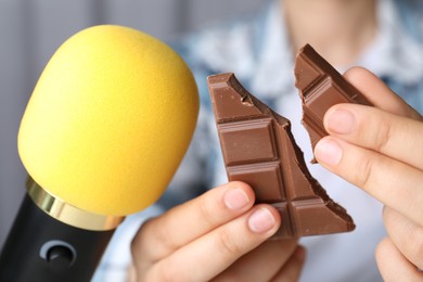Photo of Woman making ASMR sounds with microphone and chocolate, closeup