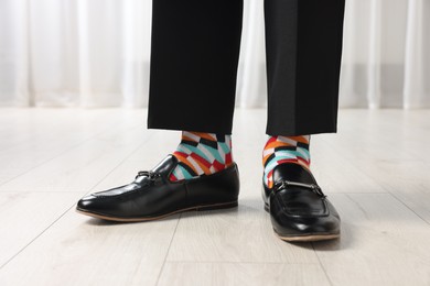 Photo of Man in stylish colorful socks, shoes and pants indoors, closeup